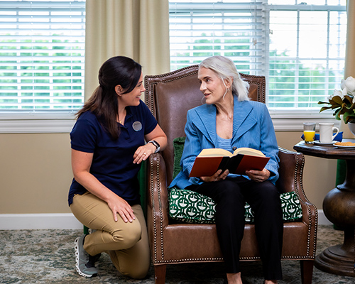 caregiver helping resident put on a necklace